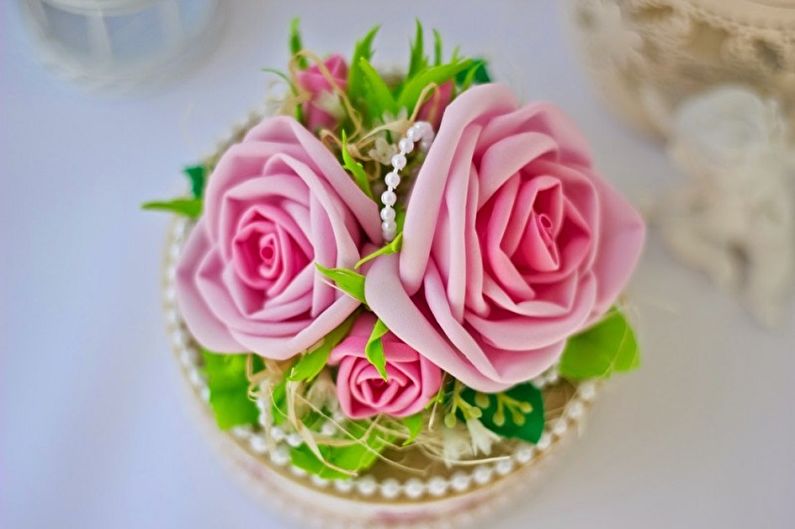 A cake decorated with pink roses and pearls.