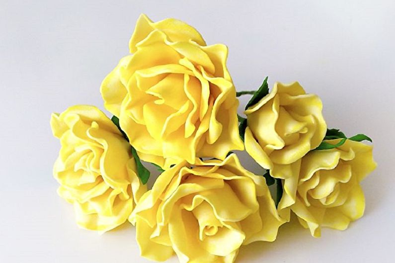 A bunch of yellow roses on a white surface.