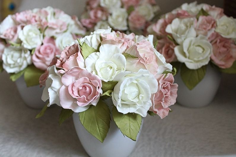 Pink and white paper roses in vases on a table.