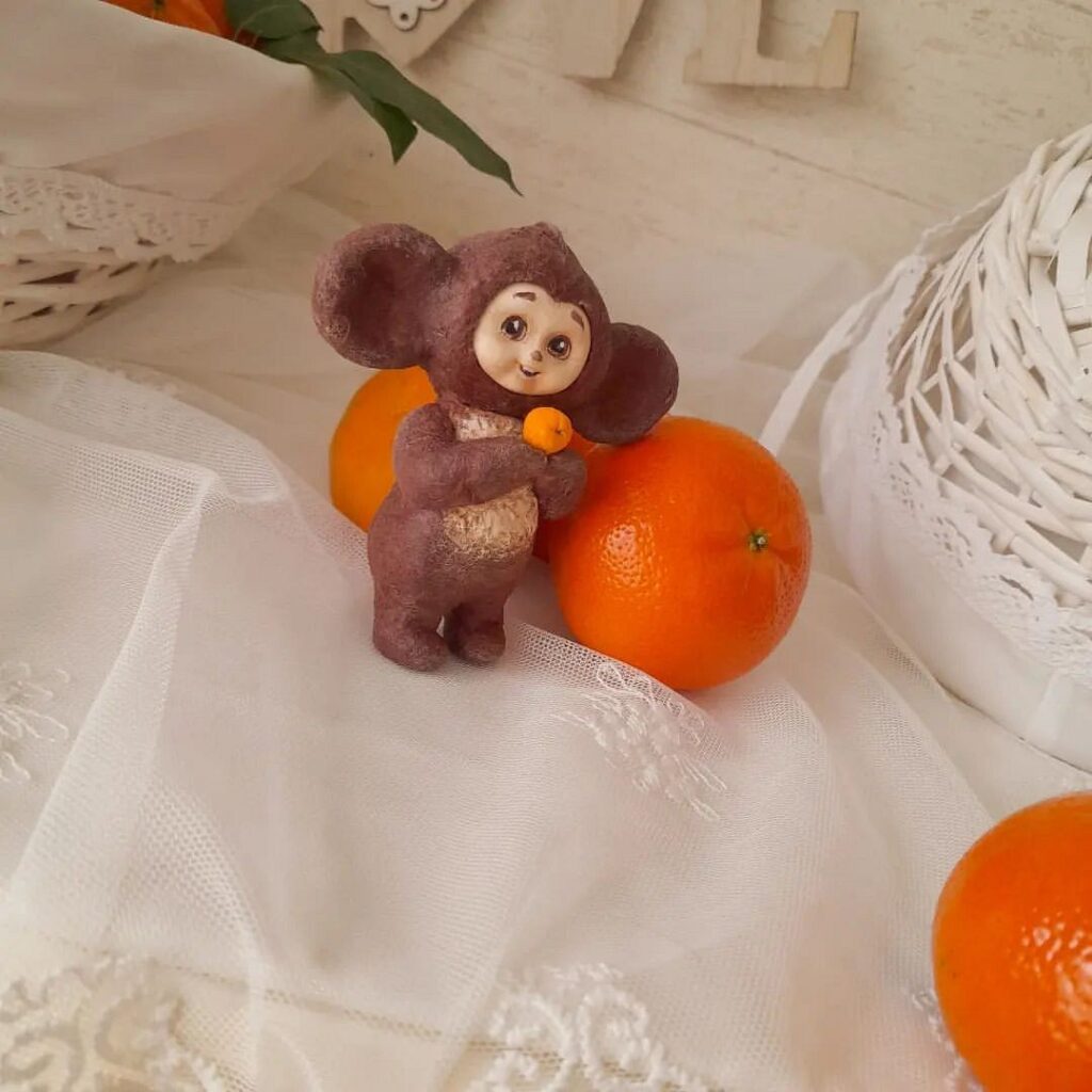 A small figurine of a monkey holding an orange.