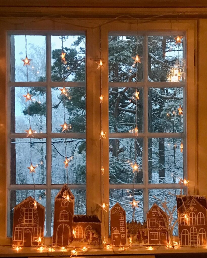 Gingerbread houses on a window sill with lights.