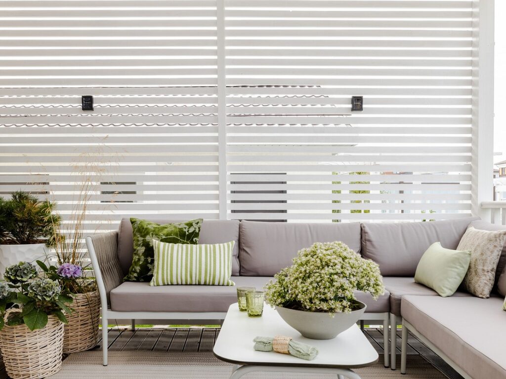 A white and grey patio with white slats and potted plants.