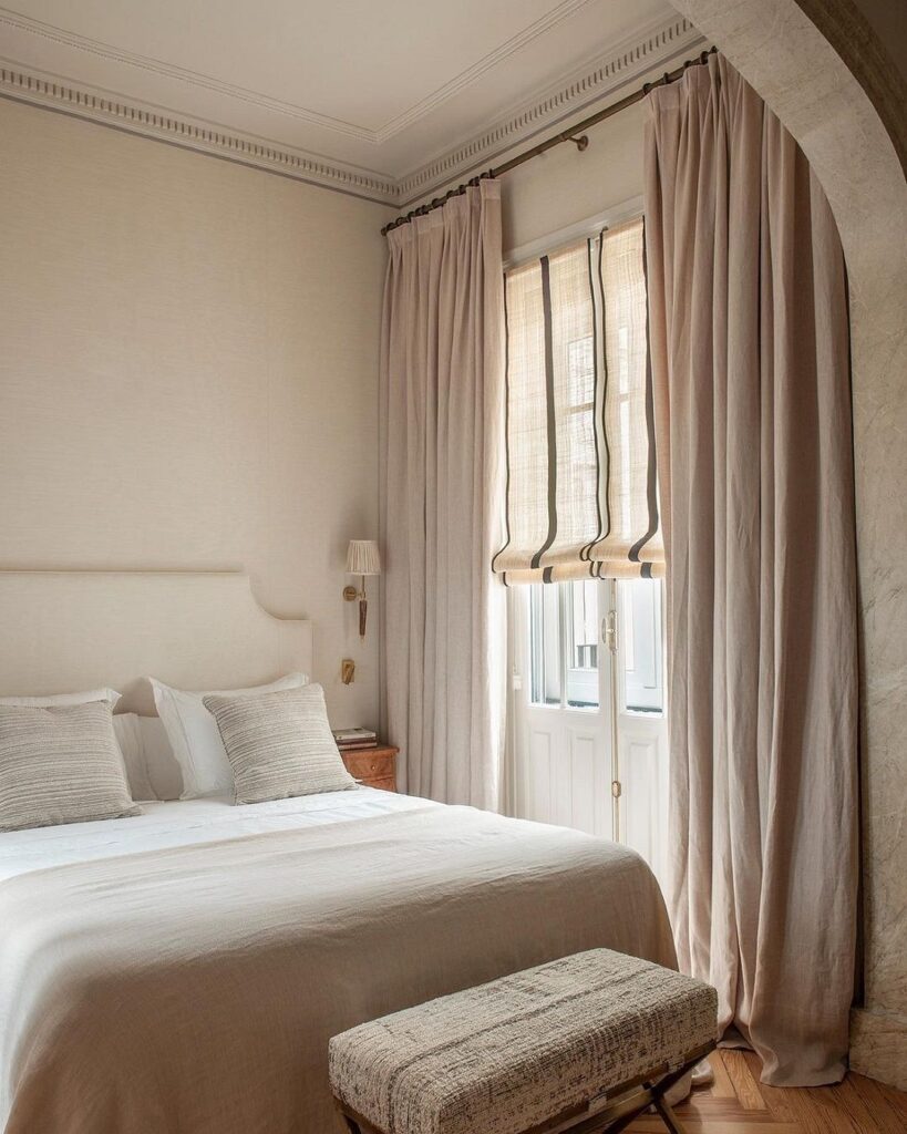 A bedroom with a white bed and beige walls.