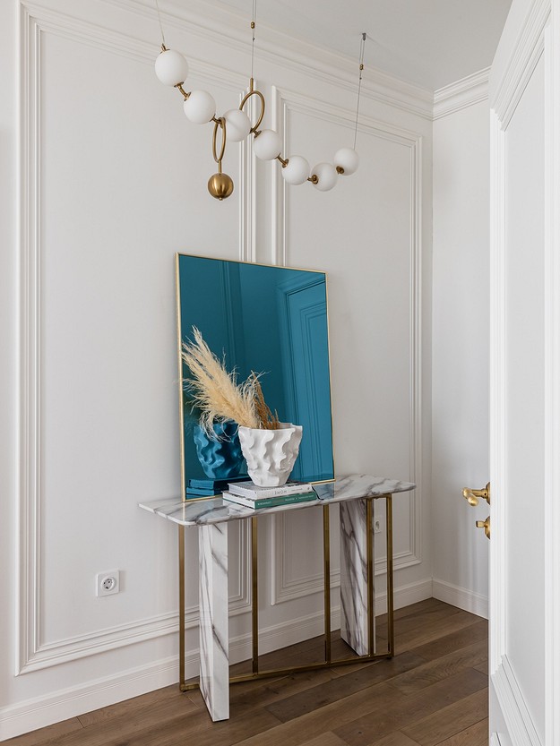 An entryway with a mirror and a blue vase.