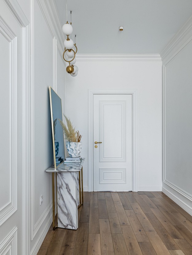 A hallway with white walls and wooden floors.