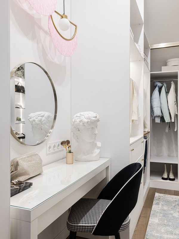 A walk in closet with a white dresser and mirror.