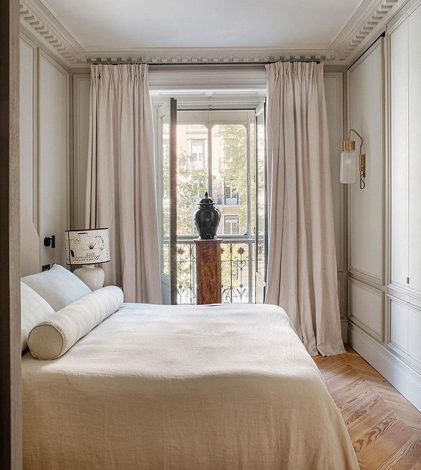 A bedroom with white walls and wooden floors.