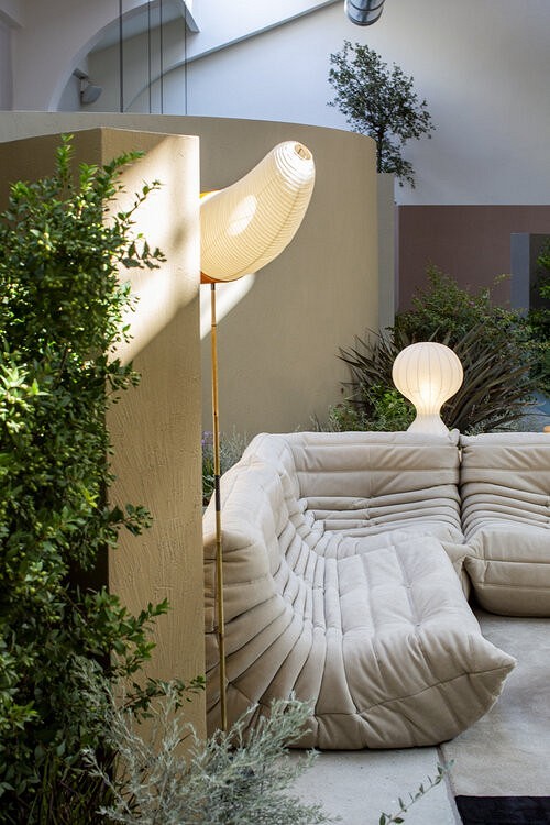 A living room with a white couch and plants.