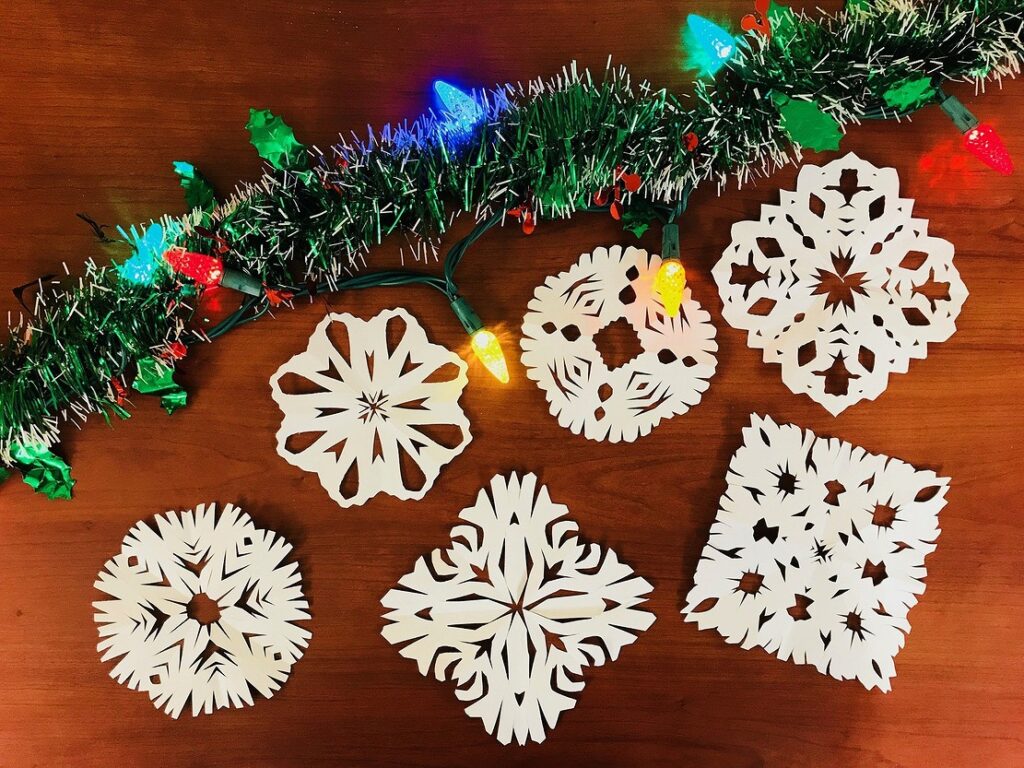 Four wooden snowflake ornaments on a wooden table.