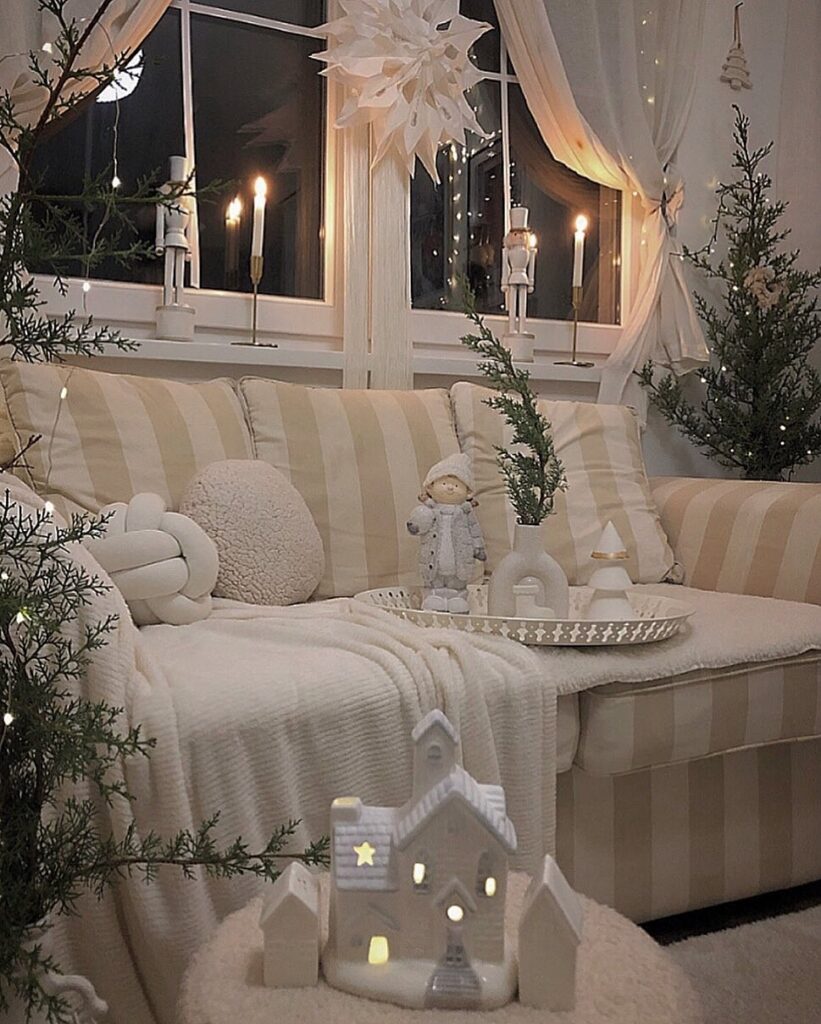 A living room decorated for christmas with a white couch and candles.