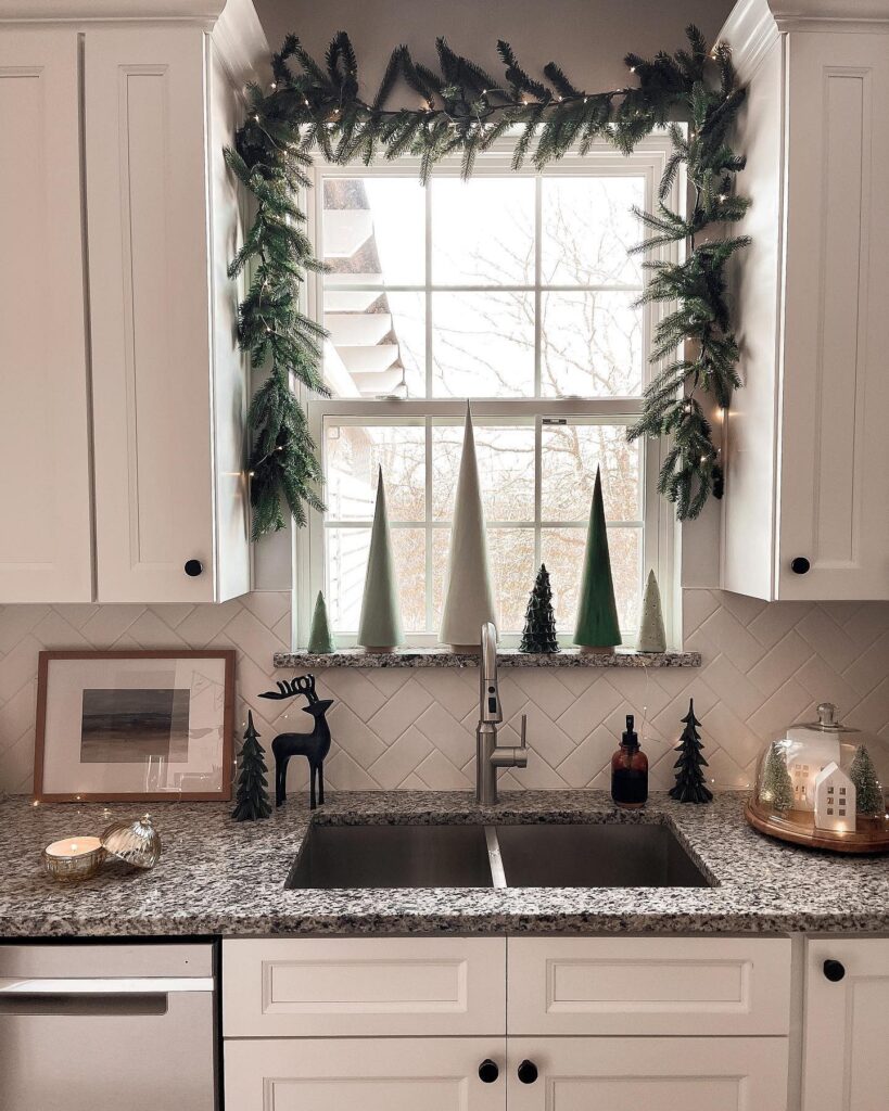 A kitchen with a christmas tree in the window.