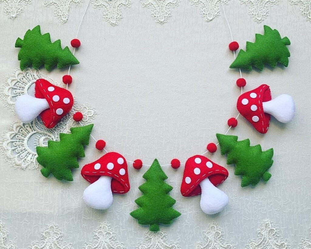 A christmas garland made of felt mushrooms and pine trees.