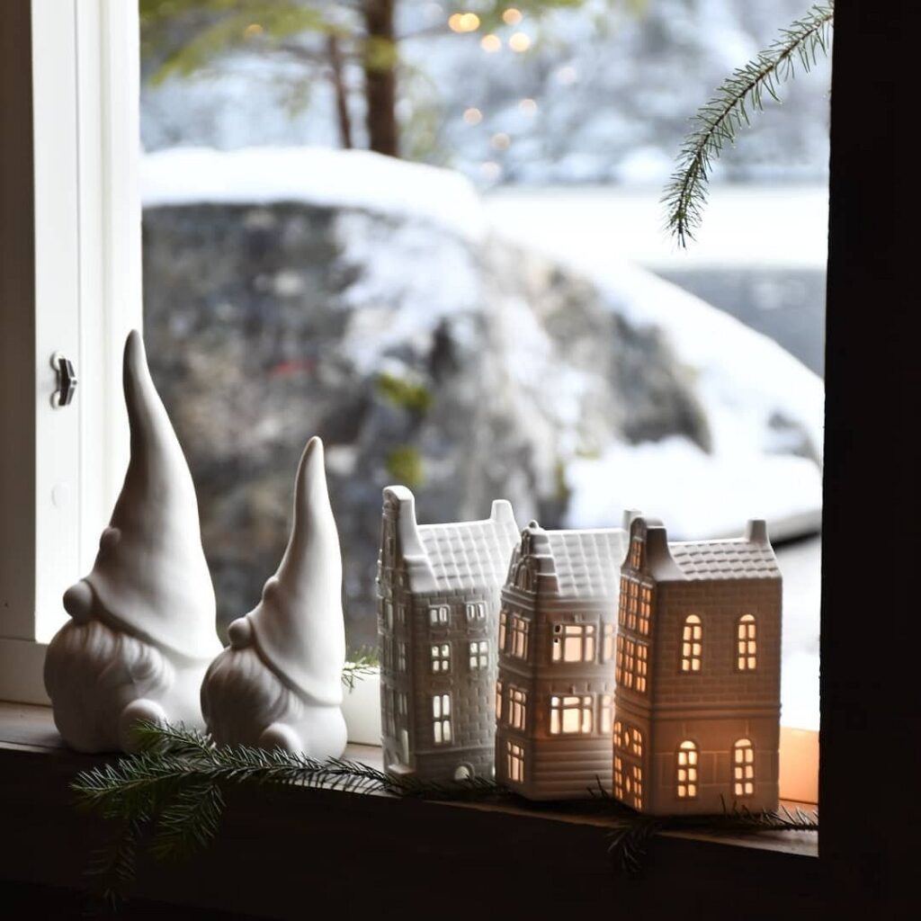 A window sill with white gnome figurines and a christmas tree.