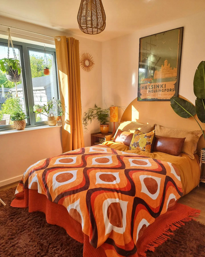 A bedroom with an orange and brown bed spread.