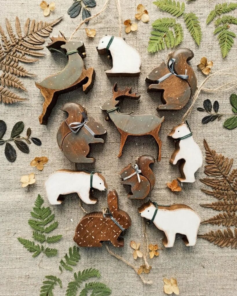 A group of wooden animals and leaves on a cloth.