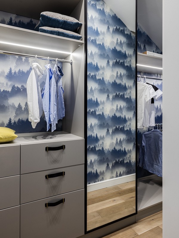 A walk in closet with blue and white wallpaper.