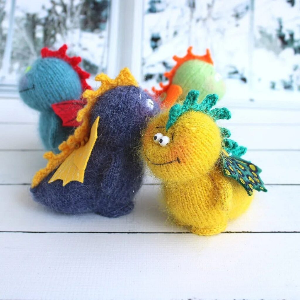 A group of knitted dragons sitting on a wooden table.