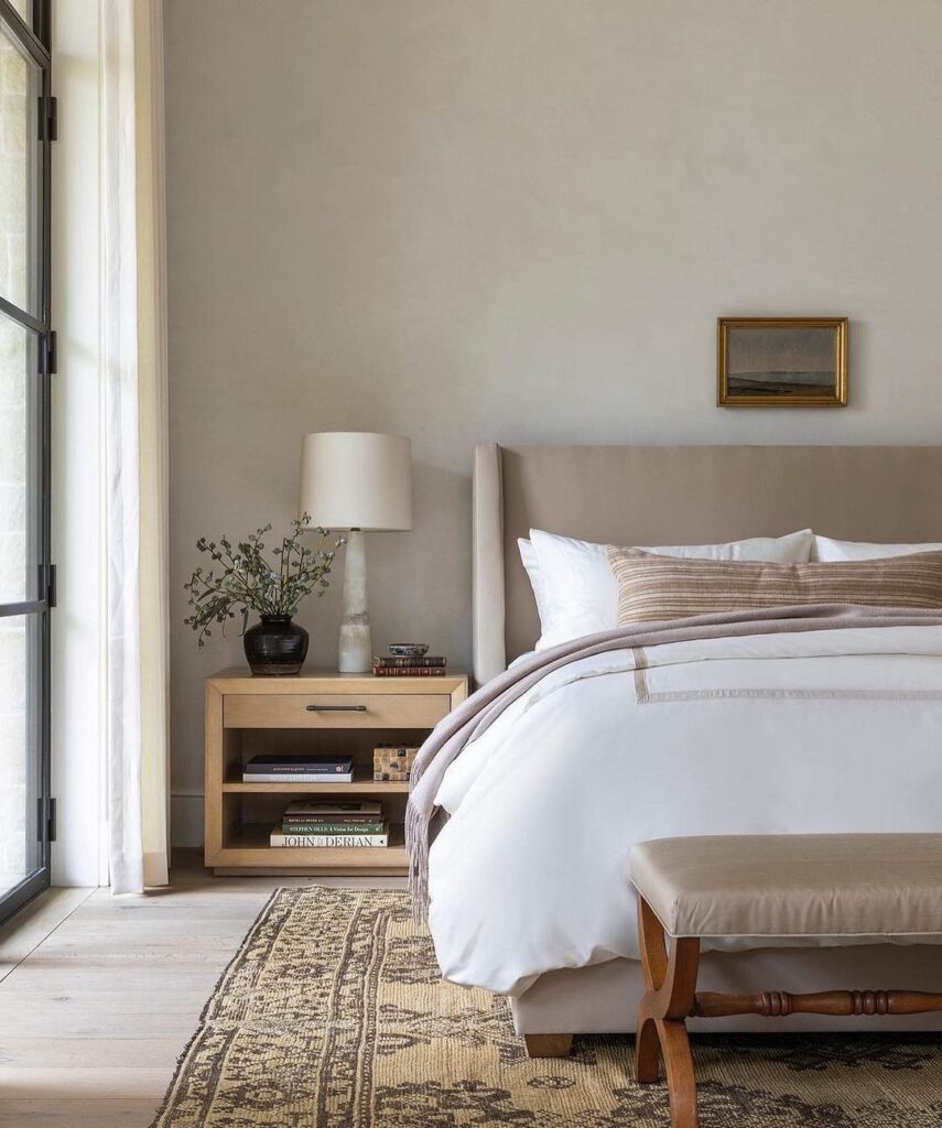 A bedroom with a white bed and a beige rug.