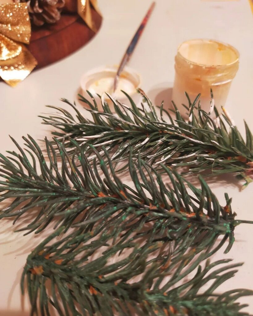 A table with pine branches and a paint brush.