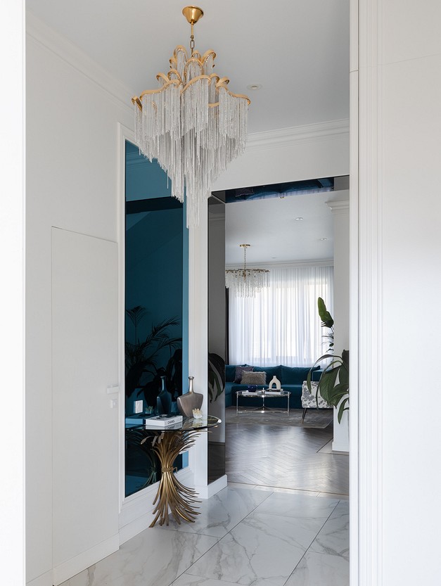 A blue and white hallway with a chandelier.