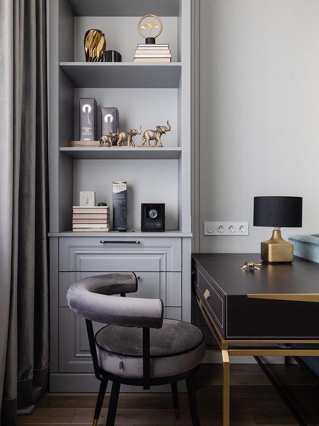 A grey and gold bedroom with a chair and bookshelf.