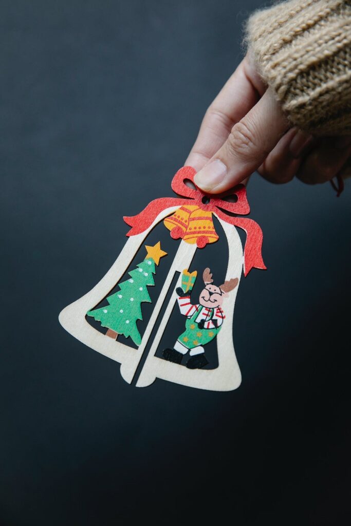 A person holding a christmas bell ornament on a black background.