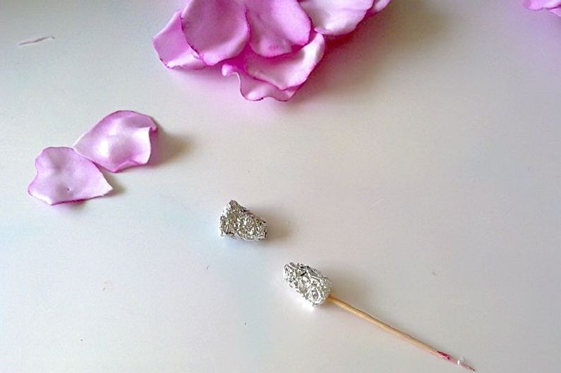 A pair of silver stud earrings with pink roses on a white table.