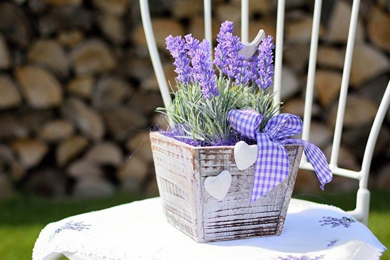 A white chair with lavender flowers in a wooden box.