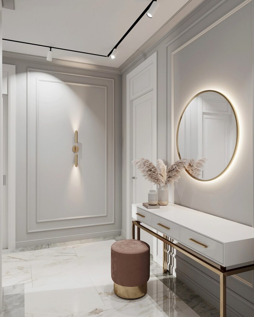 A modern entryway with a round mirror and gold accents.