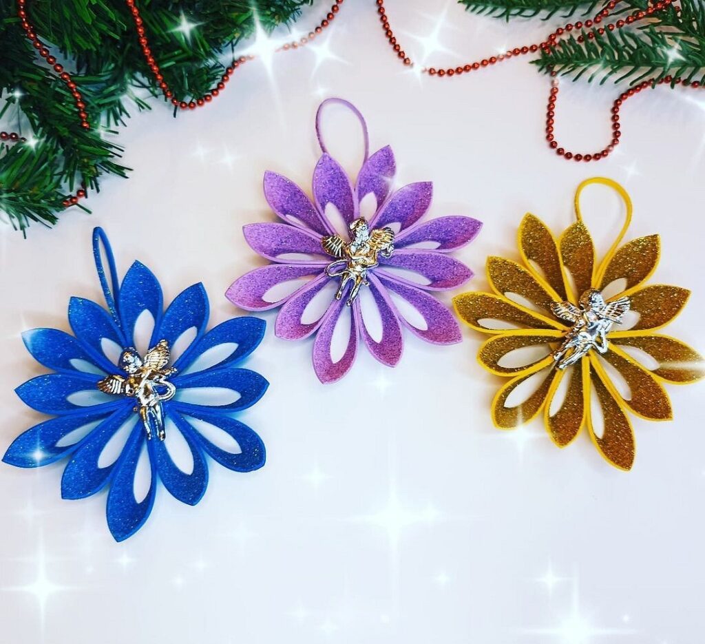 Three paper flower ornaments on a christmas tree.