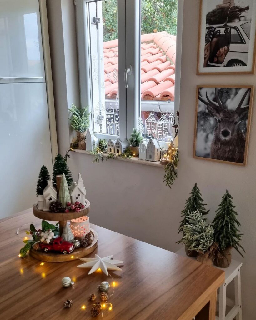 A wooden table with christmas decorations in front of a window.