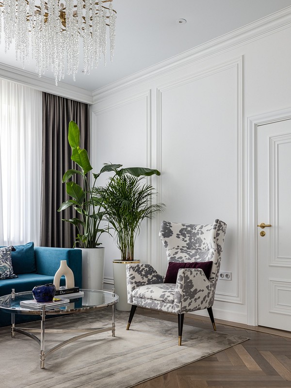 A living room with blue couches and a chandelier.