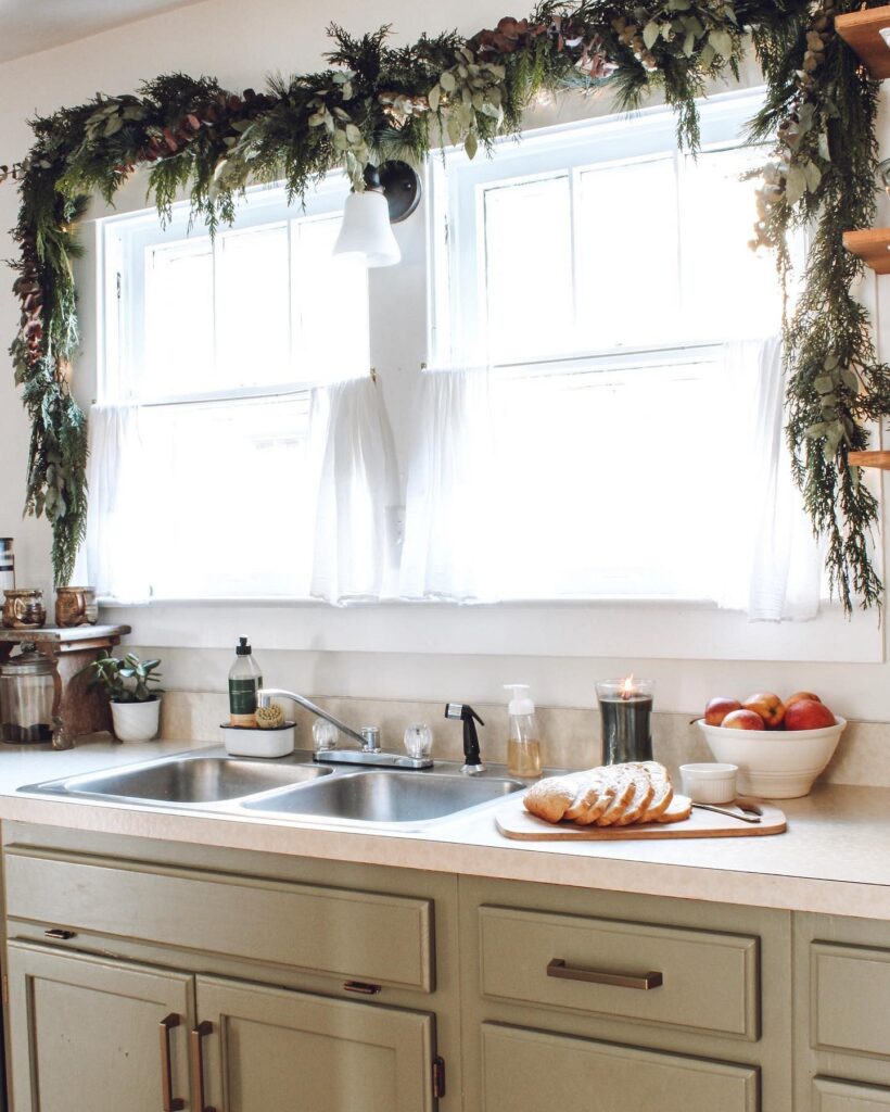 A kitchen with green cabinets and a christmas garland.