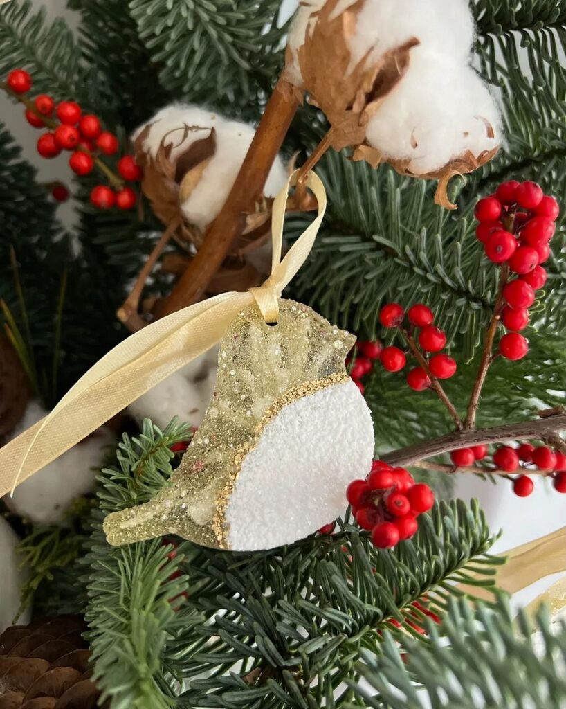 A bird ornament hangs on a christmas tree.