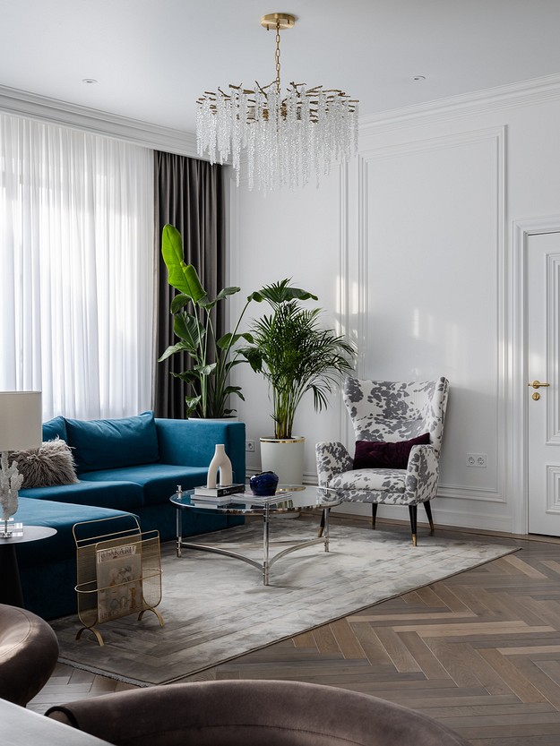 A living room with blue couches and a chandelier.