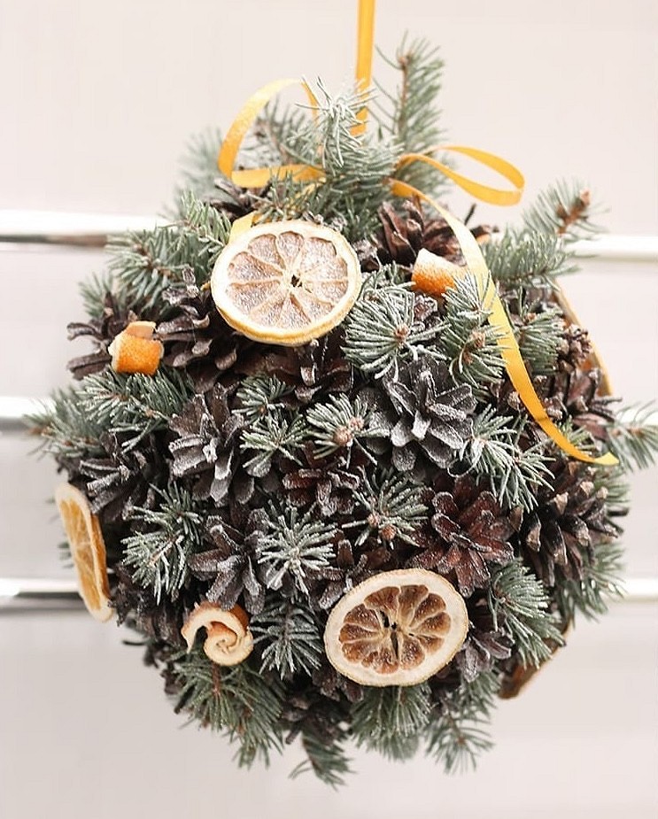 A christmas ball decorated with pine cones and orange slices.