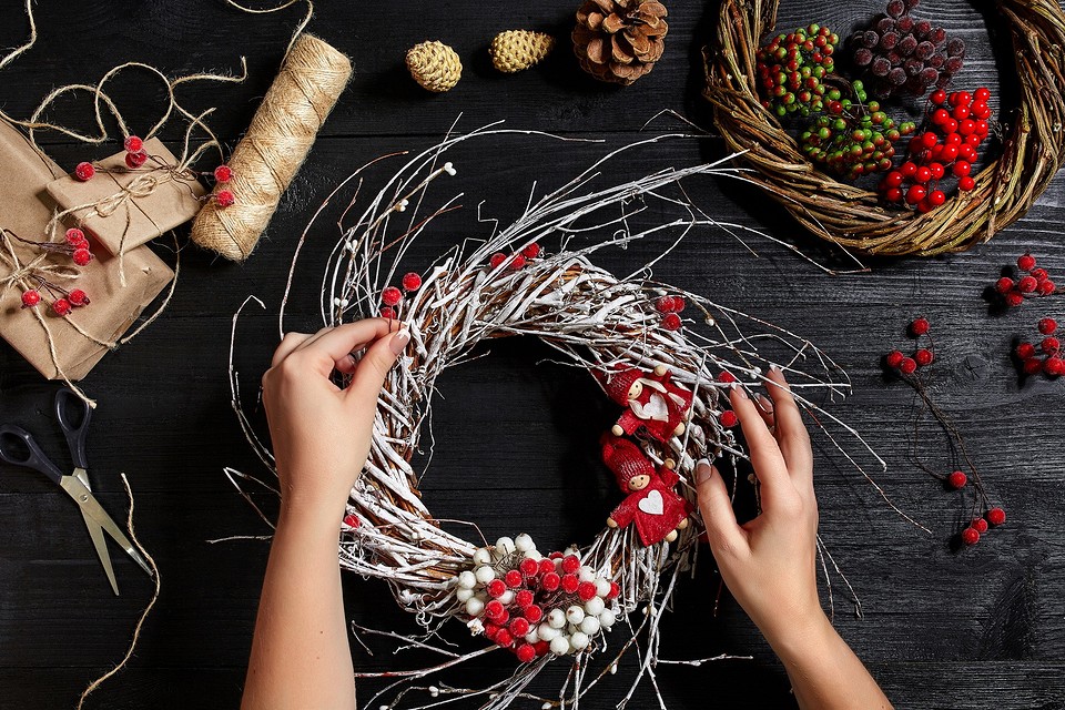 A woman is making a wreath with twigs and berries.