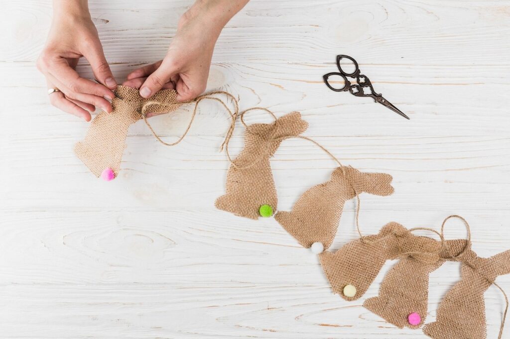 A woman is making bunny garland on a wooden table.