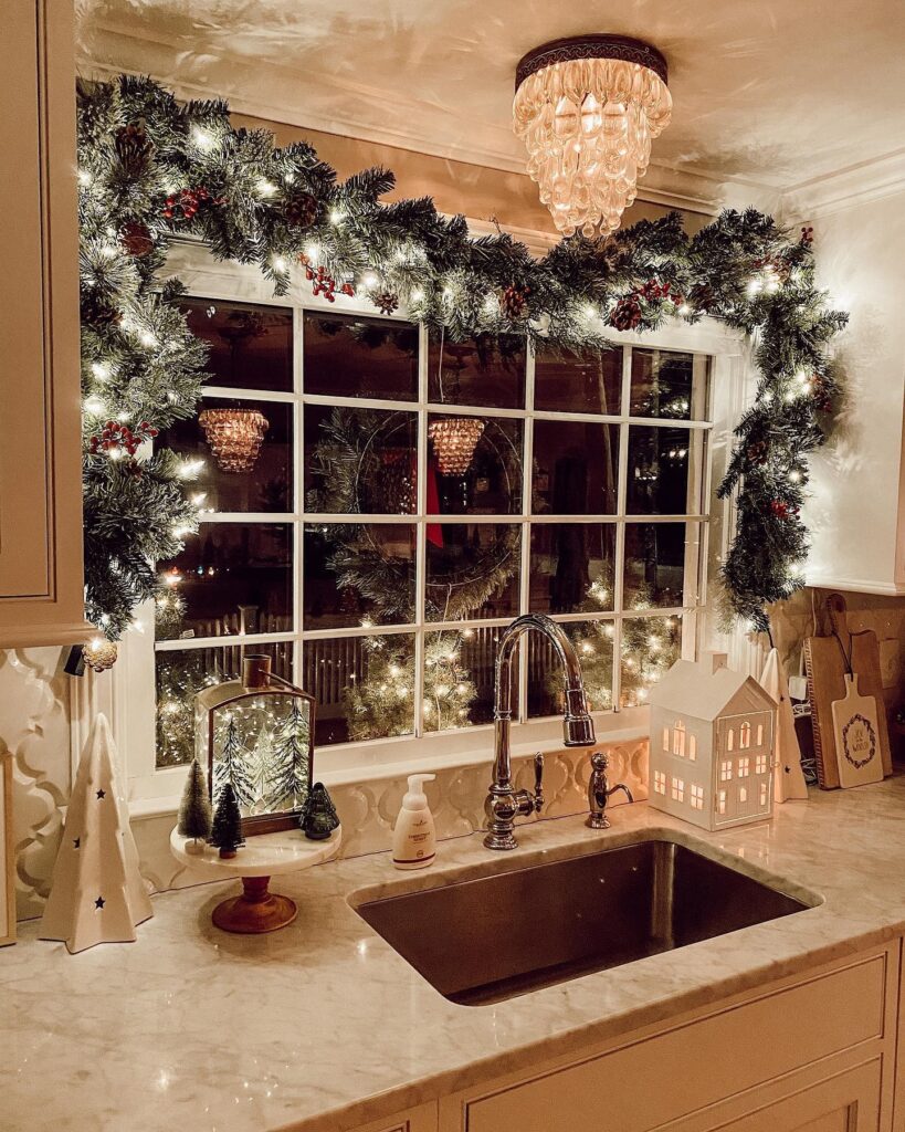 A kitchen with a christmas garland hanging over the sink.