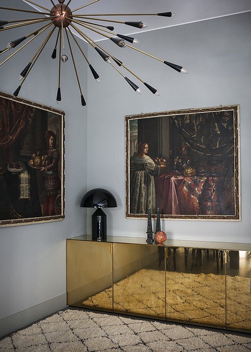 A room with a gold console and paintings on the wall.