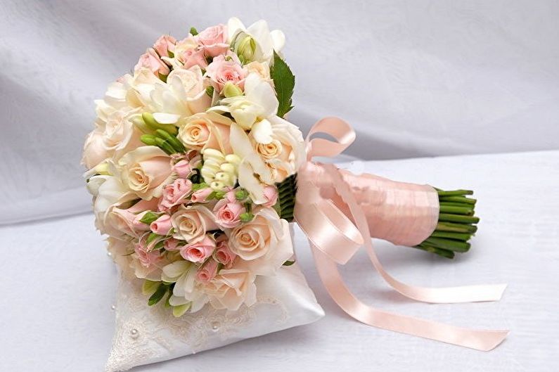 A bouquet of pink and white roses on a pillow.