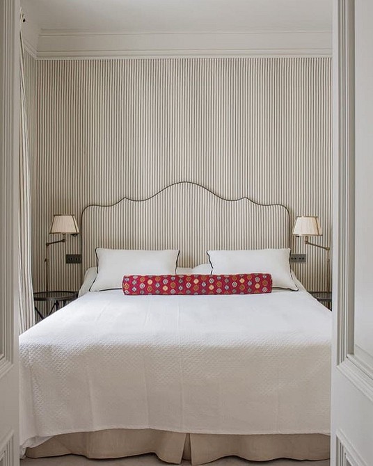 A white bed in a bedroom with striped walls.