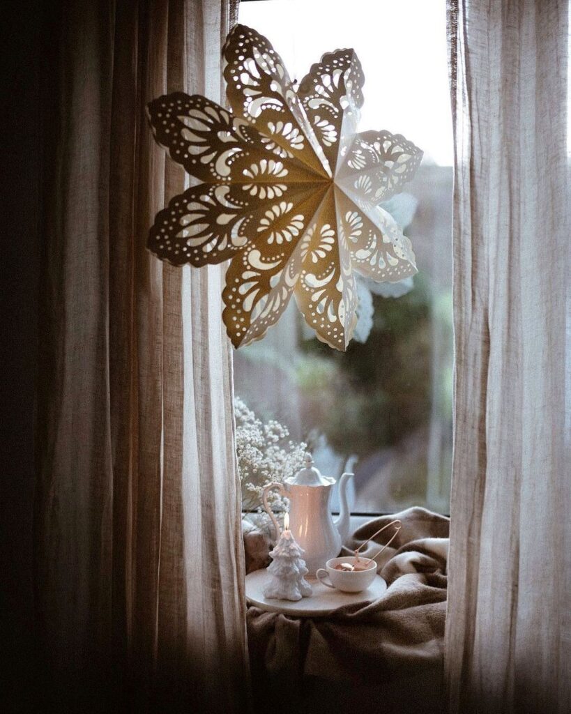 A window with a paper snowflake hanging from it.