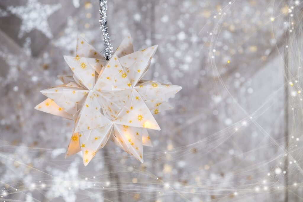 An origami star hanging on a silver background.