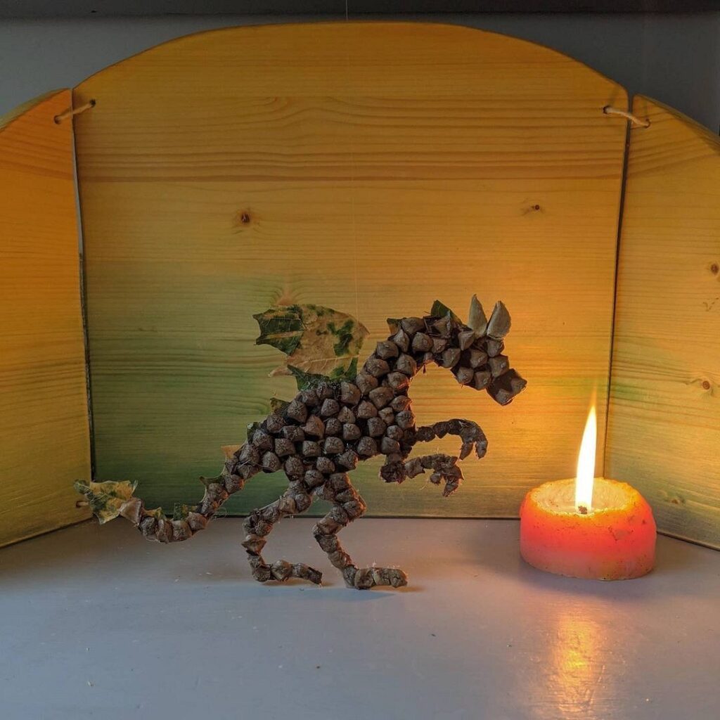 A wooden figurine of a dragon next to a candle.