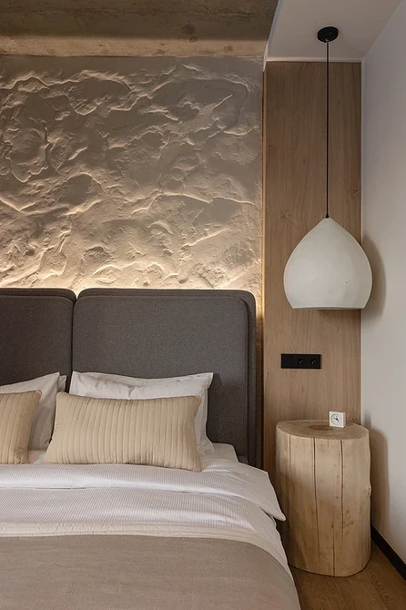 A bed in a room with a stone wall.