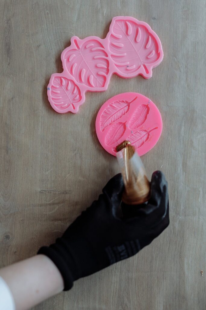 A person is using a pink silicone mold to make a cake.