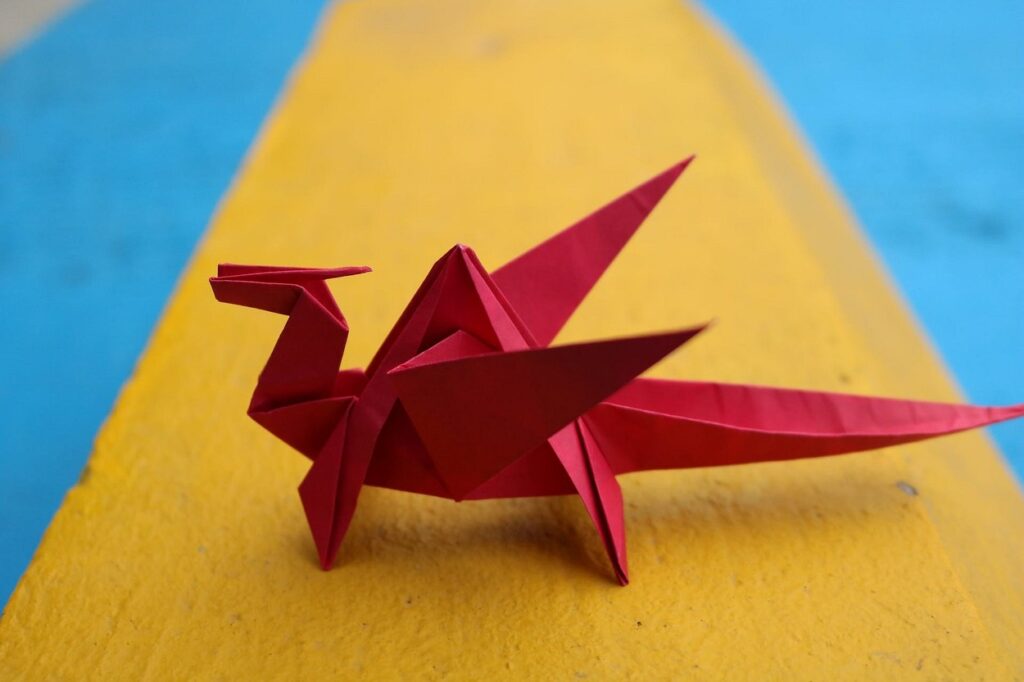 A red origami dragon on a yellow background.