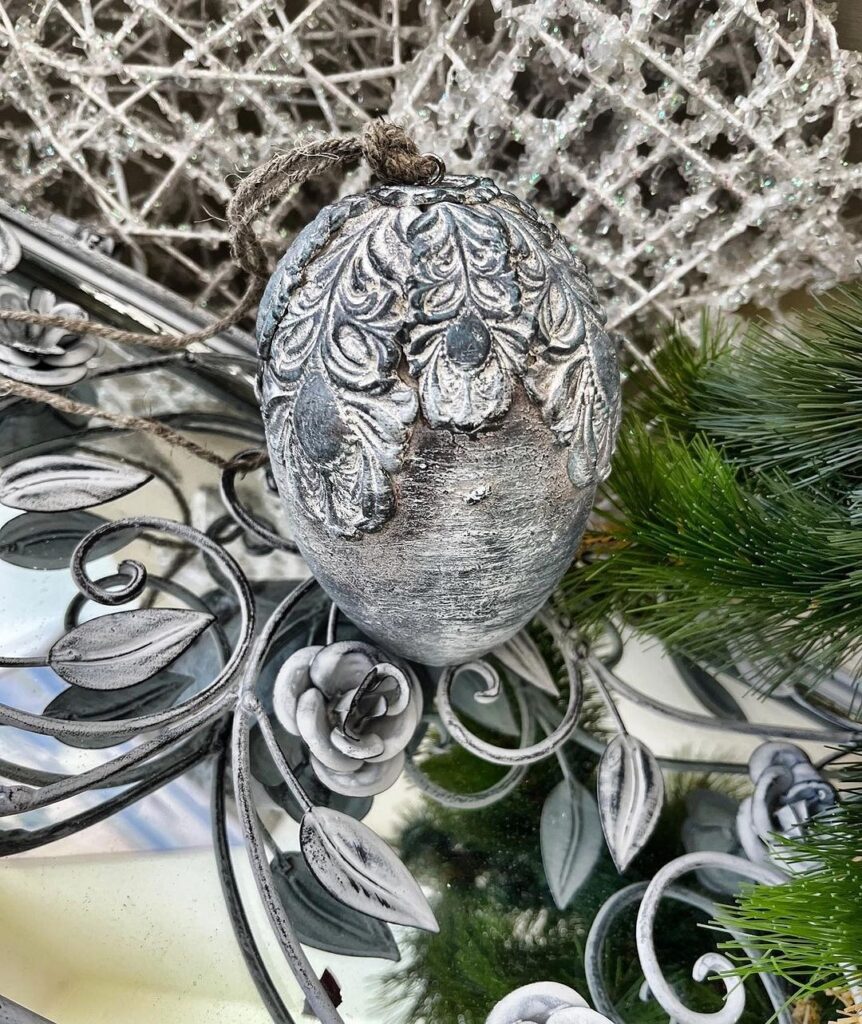 A silver ornament hangs on a christmas tree.