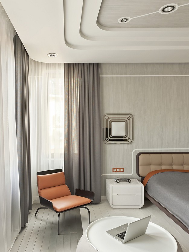 A modern bedroom with a white bed and orange chair.
